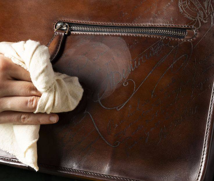 A leather bag being hand-polished with a soft cloth