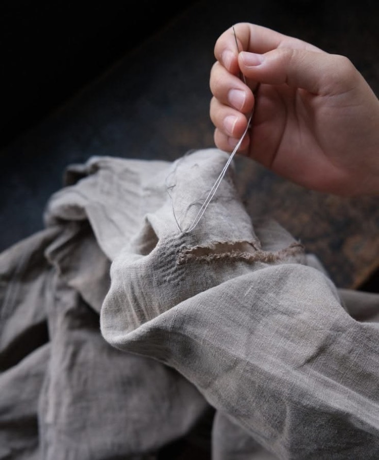 A torn garment being mended with needle and thread